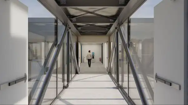 long glass hallway with carpet and a man at the end of the corridor