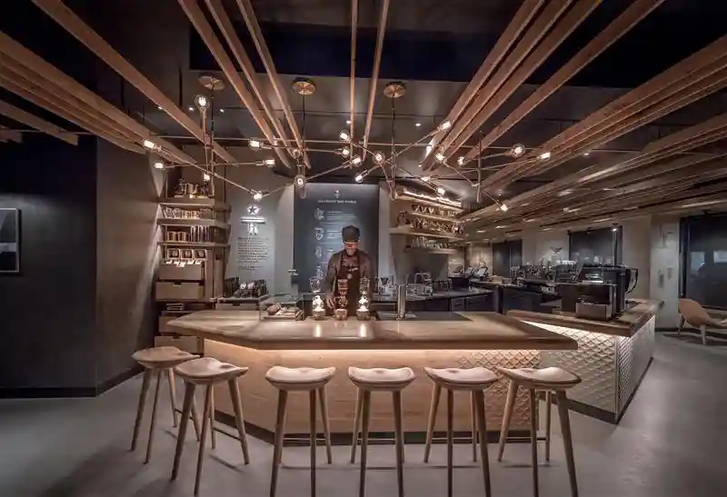 Starbucks interior wooden bar and stools with man making coffee behind counter